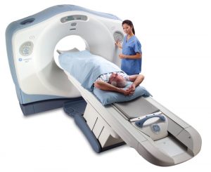 Person going into a CT Scan unit with a medical professional standing nearby